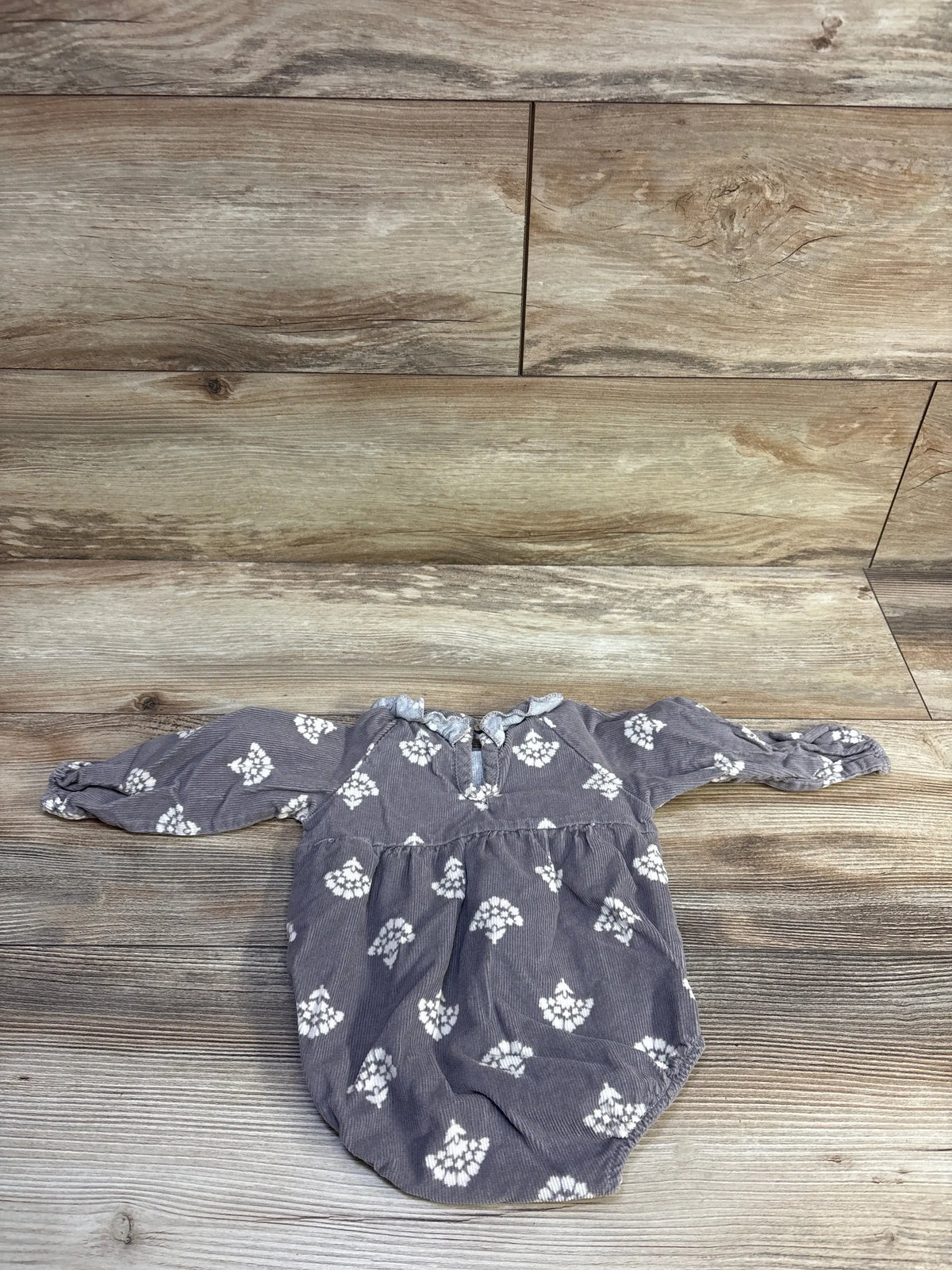 Flat lay of Rabbit and Bear grey long sleeve bubble romper with ruffled collar, keyhole tie and white floral print on wood