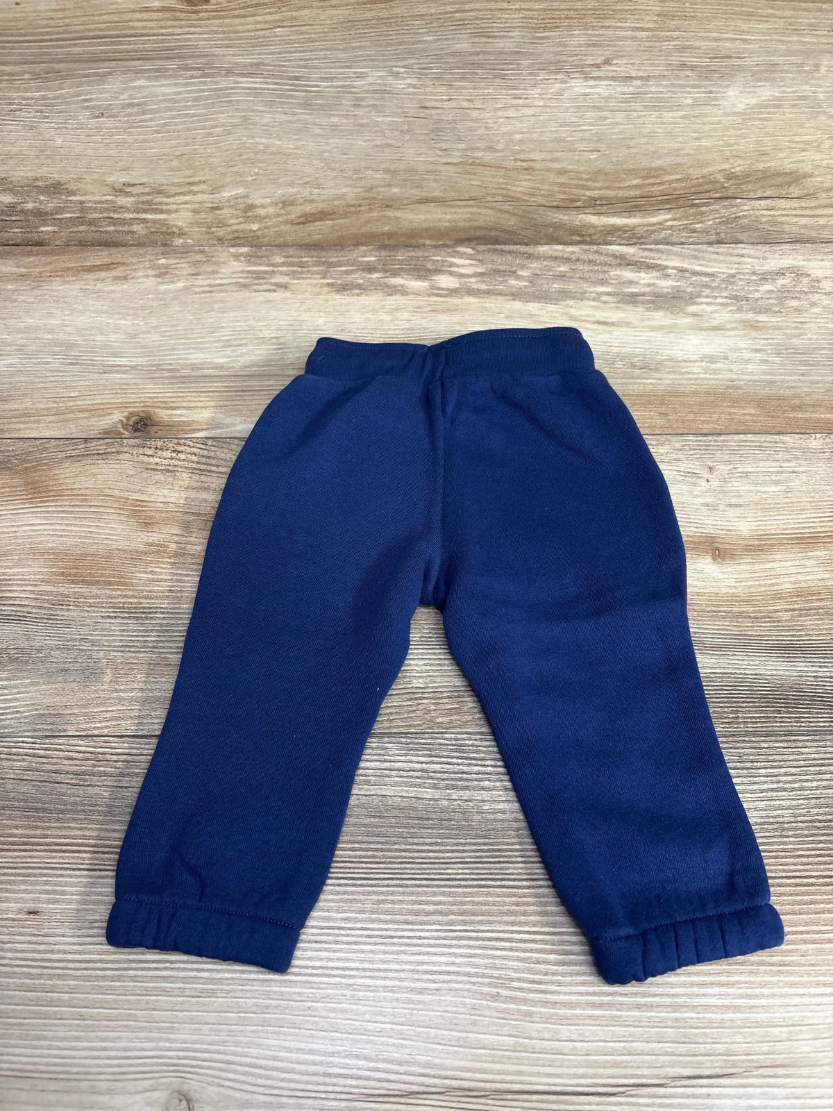 Navy blue toddler fleece sweatpants with elastic cuffs on wooden floor background