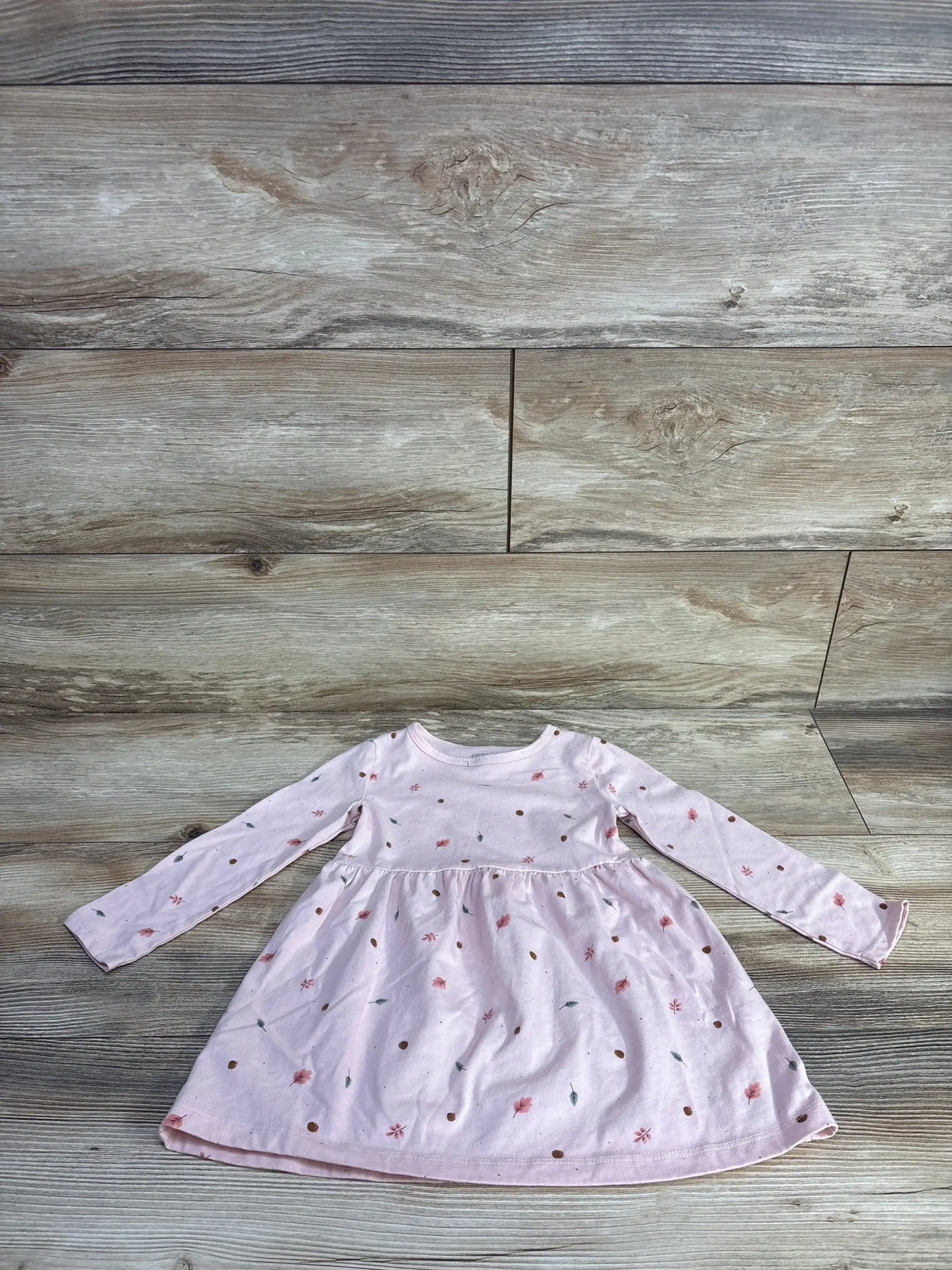 Flat lay of Carters Long Sleeve Dress in pink with tiny ditsy floral print and gathered skirt on wood plank floor