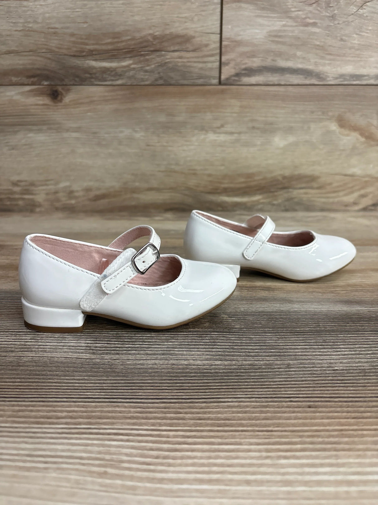 White patent leather girls Mary Jane dress shoes with buckle on wooden floor