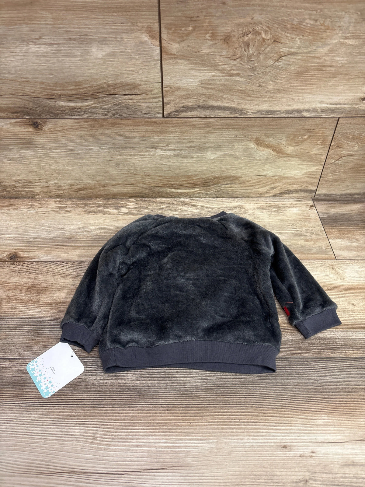 Flat lay of Disney Baby Mickey Mouse plush pullover sweatshirt in grey with ribbed cuffs and hem on wood background