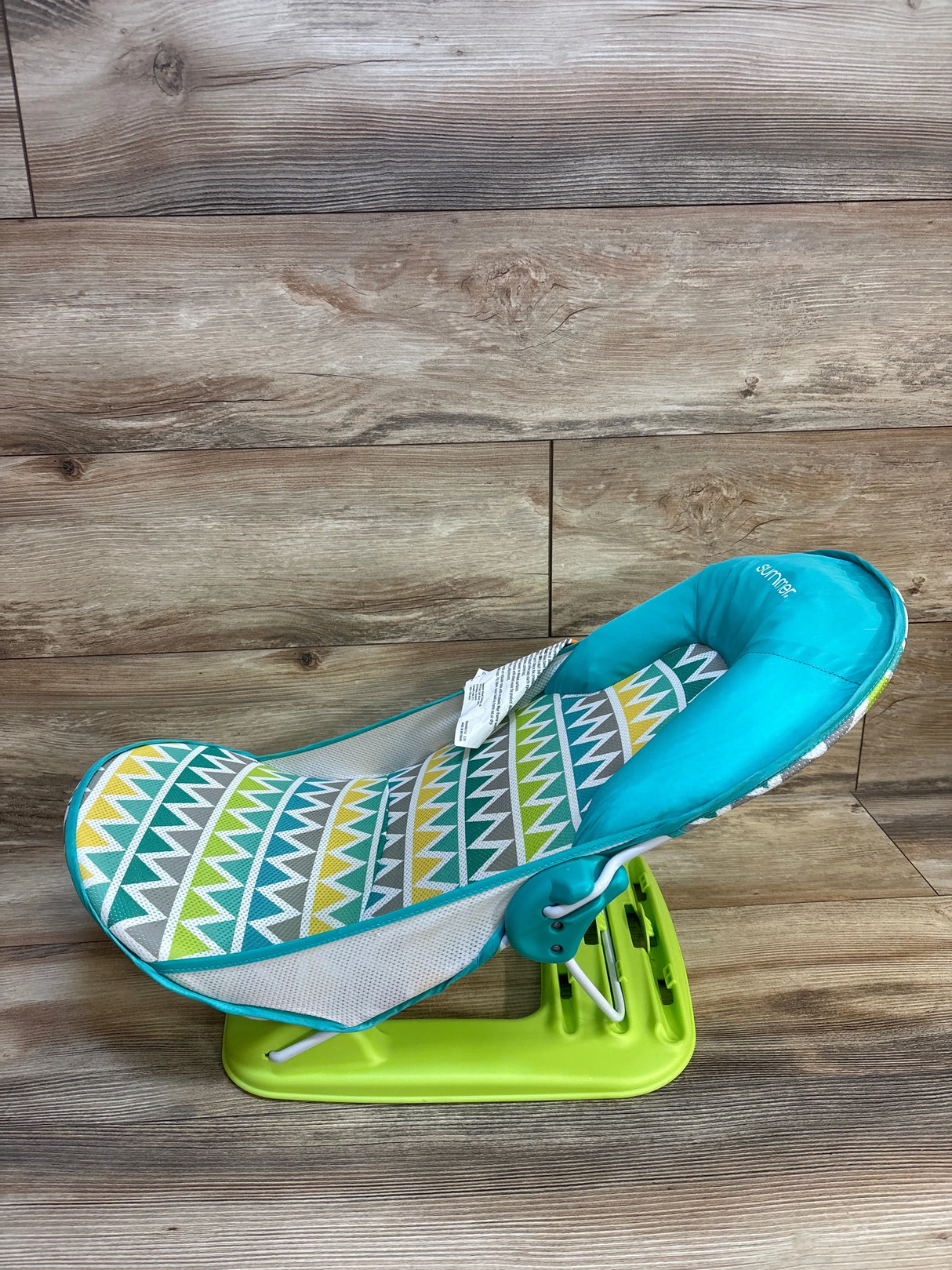 Colorful baby bouncer seat with geometric pattern on wooden floor, used baby gear resale.