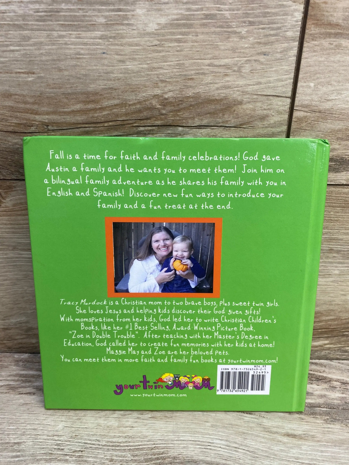 Back of Austin Loves His Family hardcover showing green back with author photo, blurb, logo and barcode on wood background