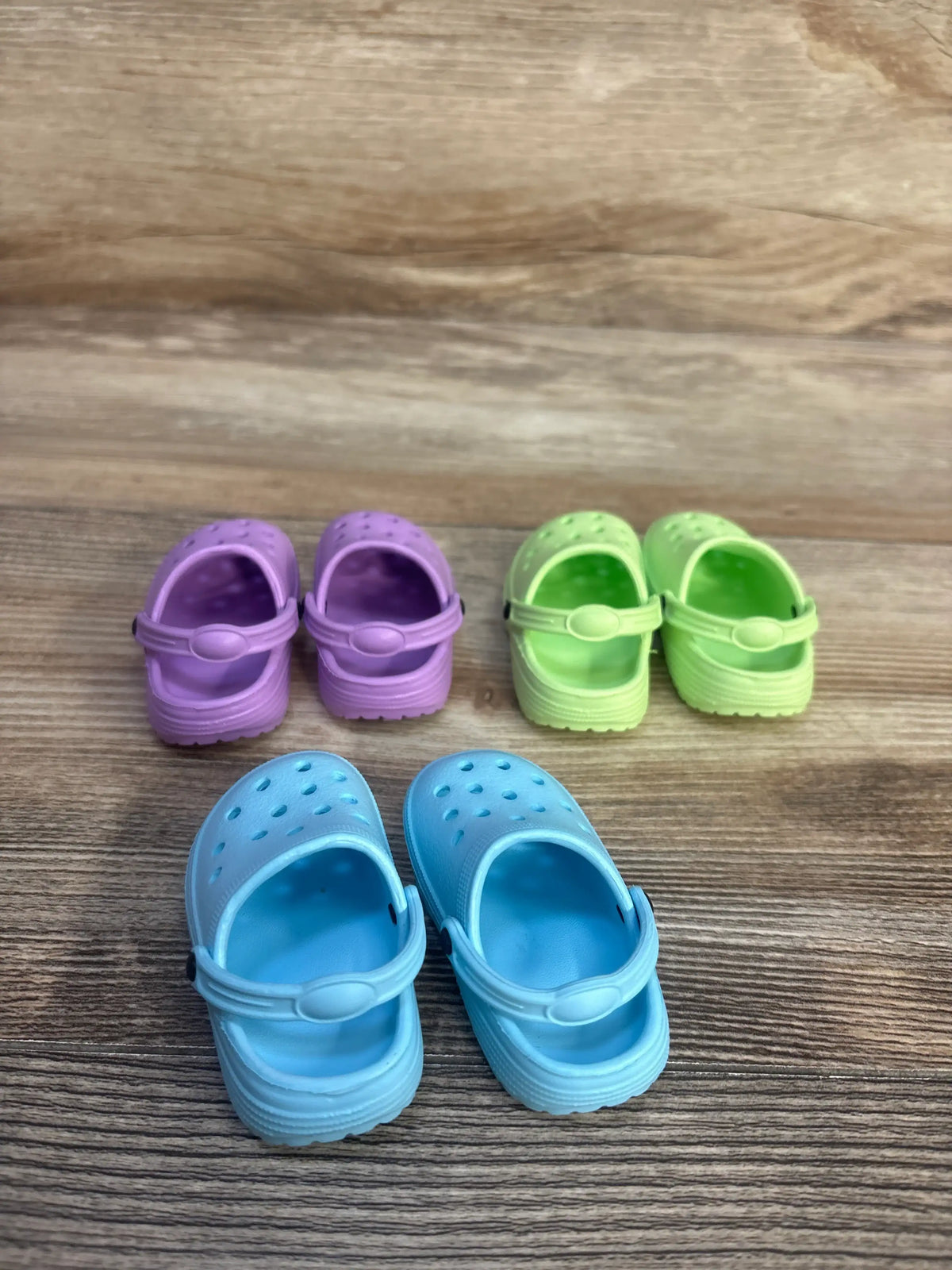 Front view of HXIELEC 3pk Clog Shoes for Doll showcasing purple green and blue pairs with heel straps on wood grain