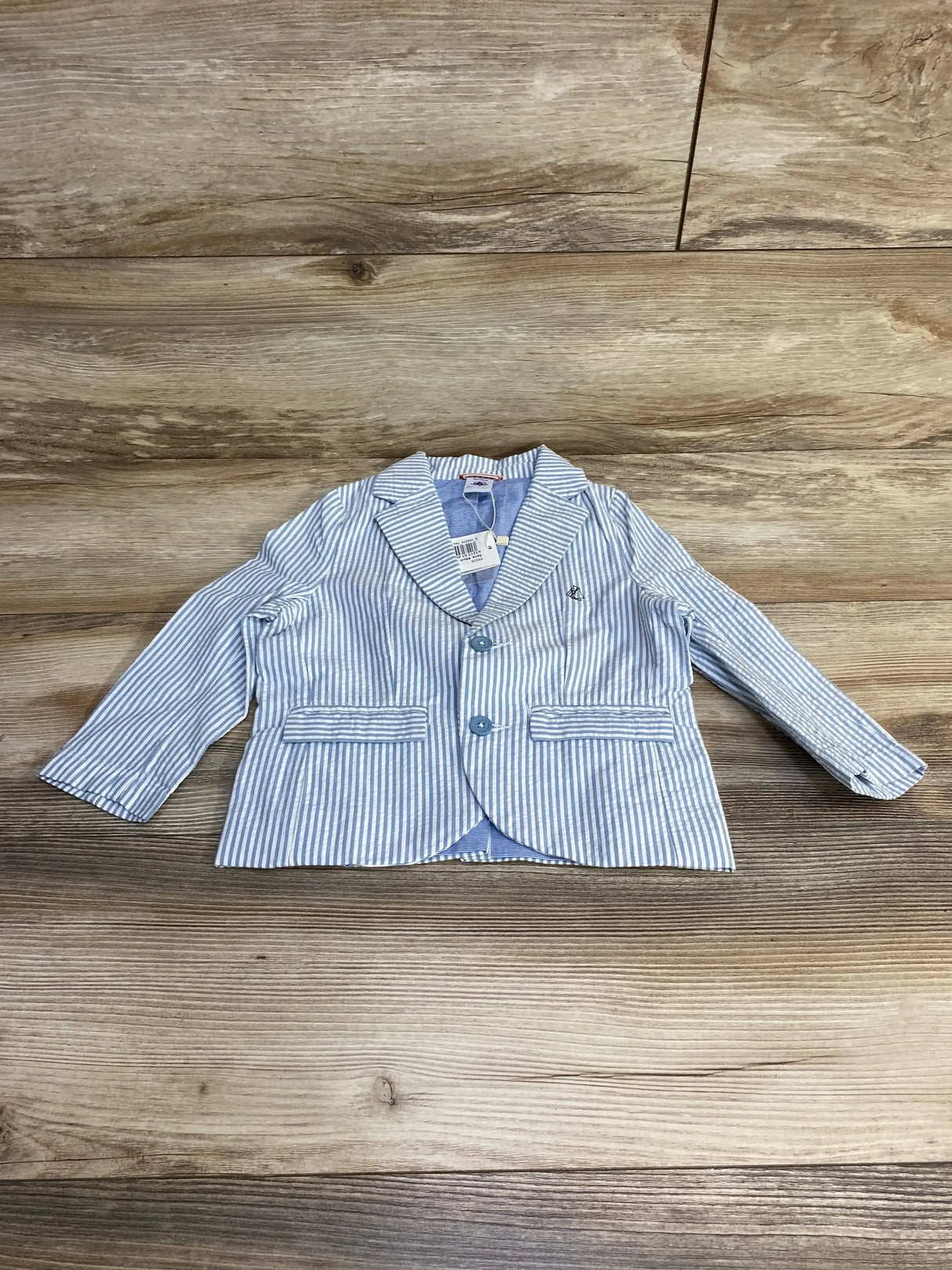 Front view of toddler blue-and-white Petite Bateau blazer with notch lapel, two buttons, and welt pockets on wood floor