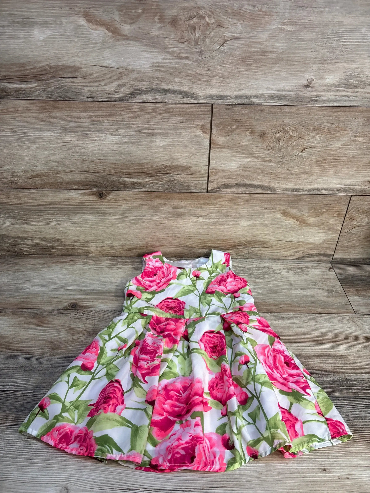Toddler girl floral dress with pink roses and green leaves on wood background