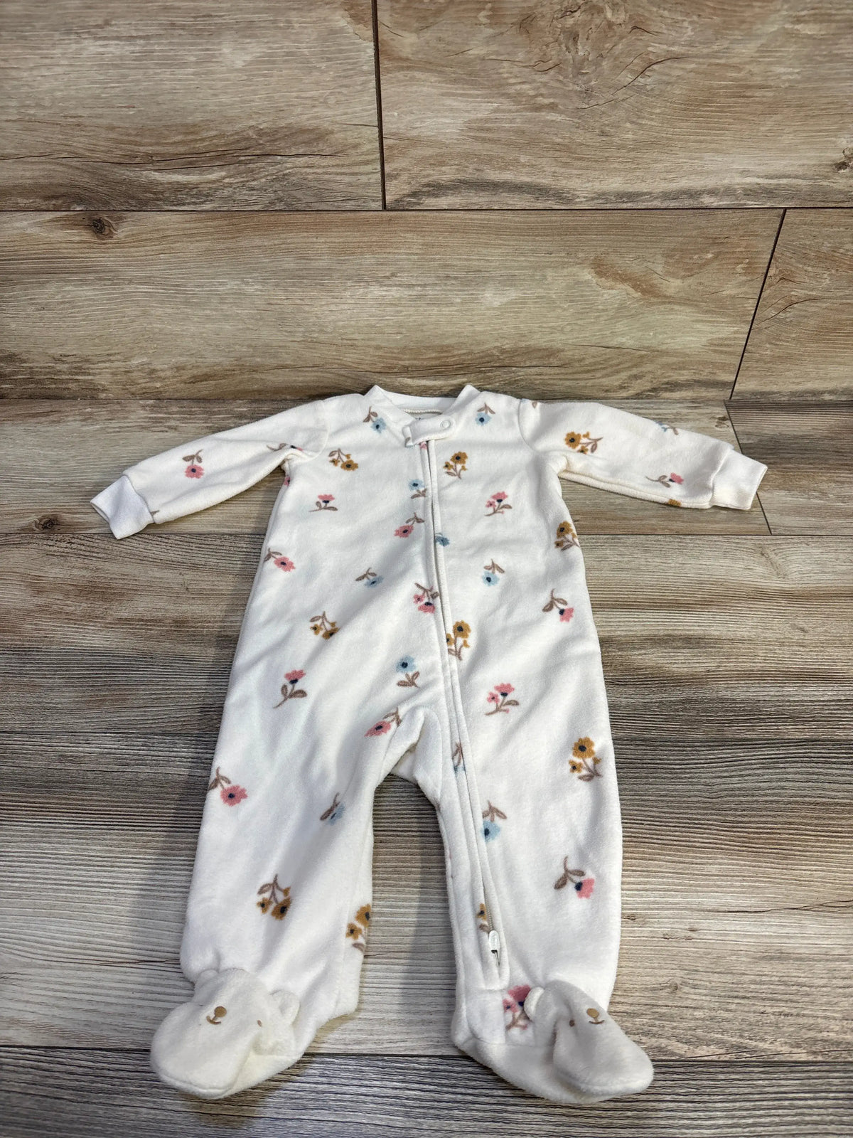 Front view of Carter’s ivory blanket sleeper with floral print, footed legs, and full-length zipper on wood-look flooring