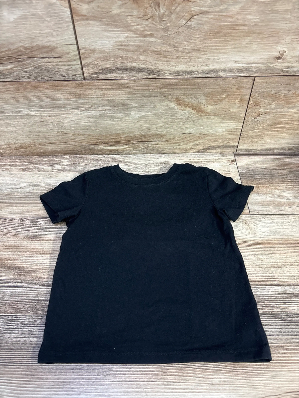 Flat lay of Cat & Jack black short-sleeve toddler t-shirt size 4T showing crew neck on wood background