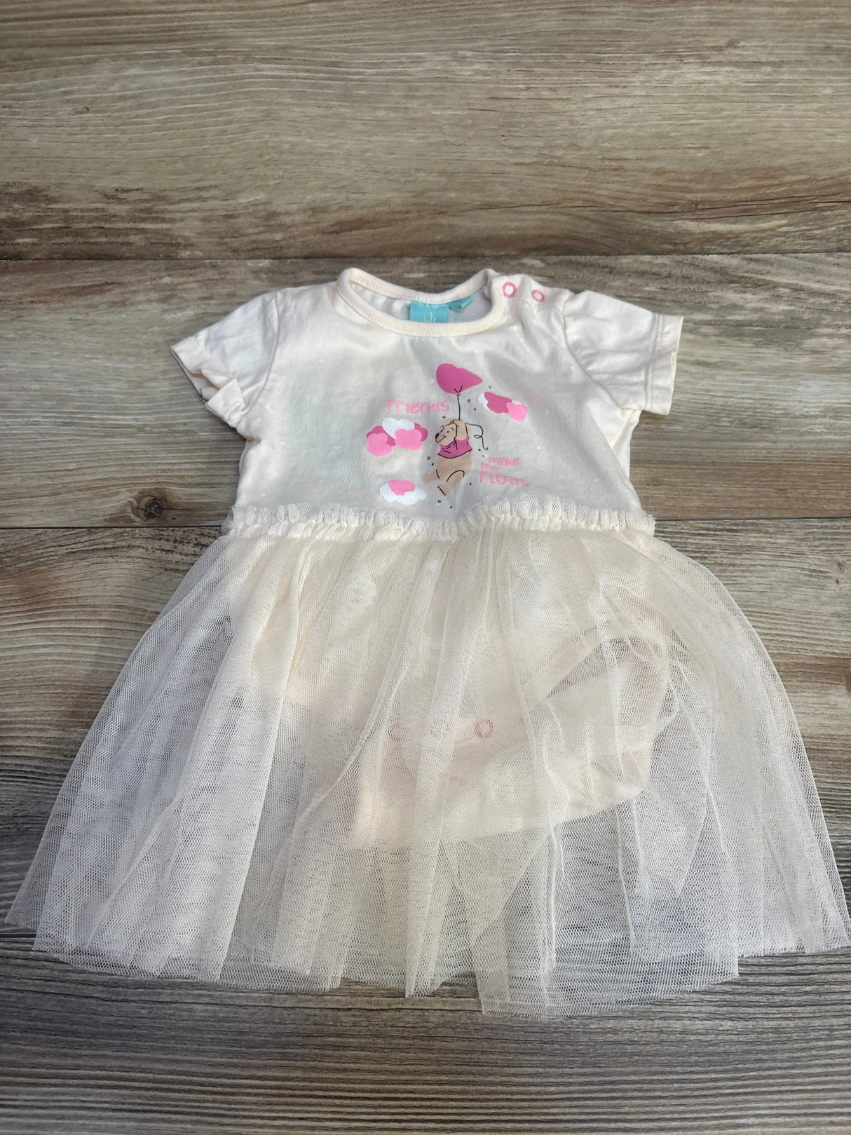 Baby girl white tulle dress with pink accents, short sleeves, and animal print bodice, laid flat on wood
