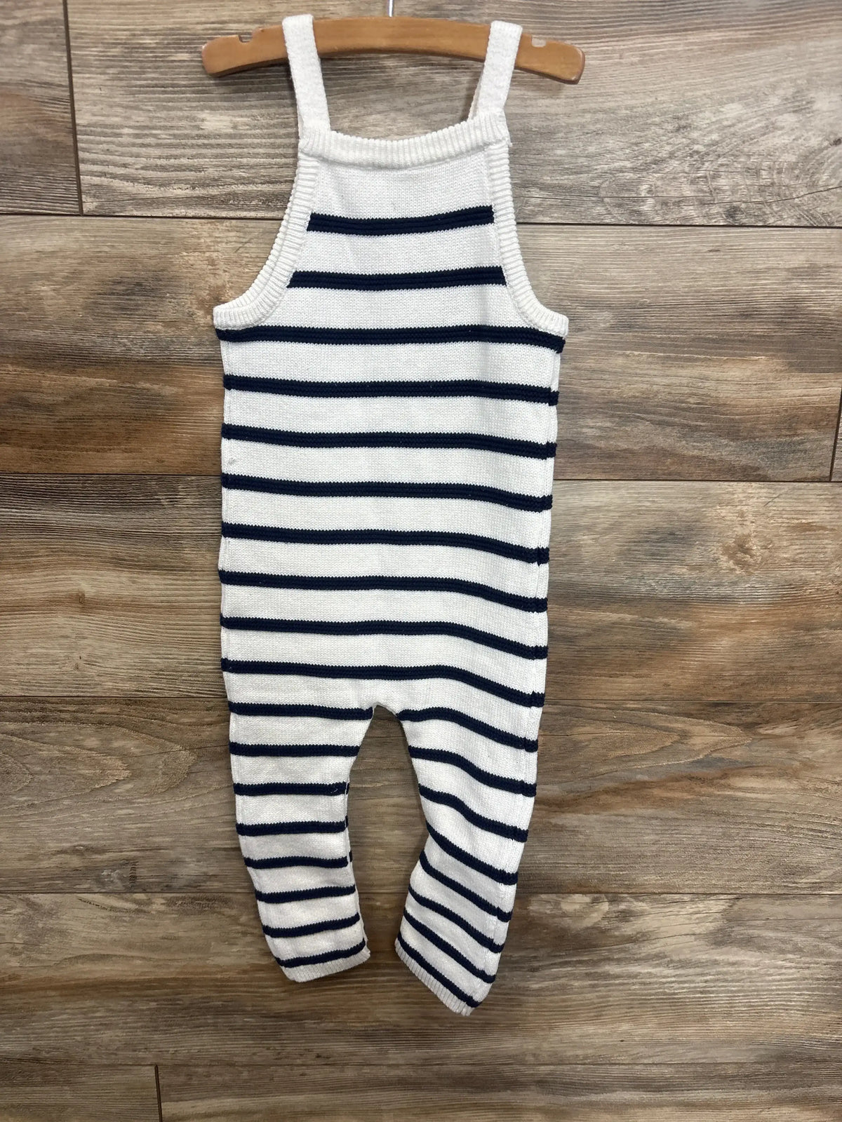 Striped knit baby romper with navy and white pattern, displayed on wooden hanger