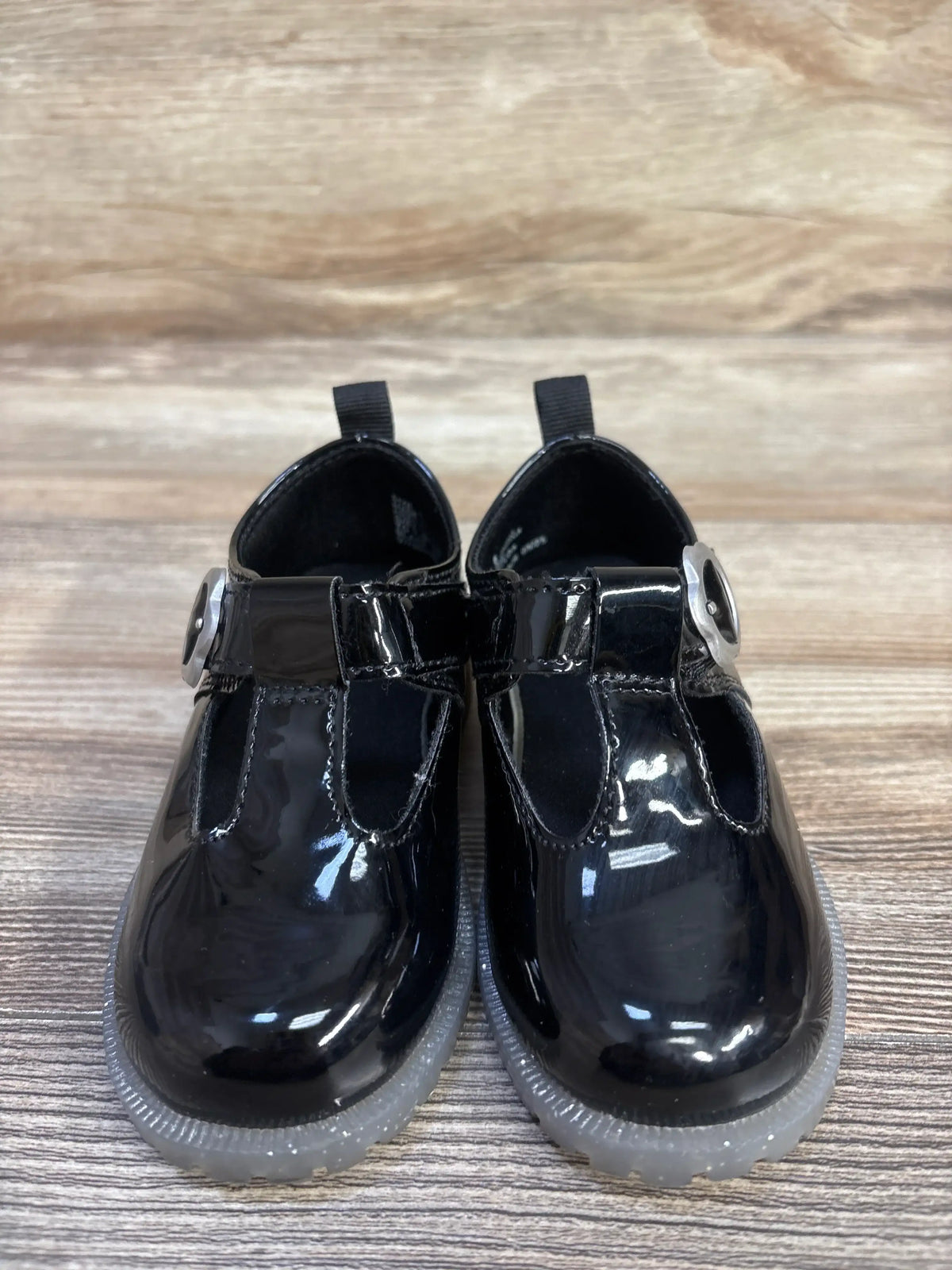 Front view of Baby Gap T-strap loafers, size 6C, showing black vegan patent leather, metal buckles, and rubber gripper soles