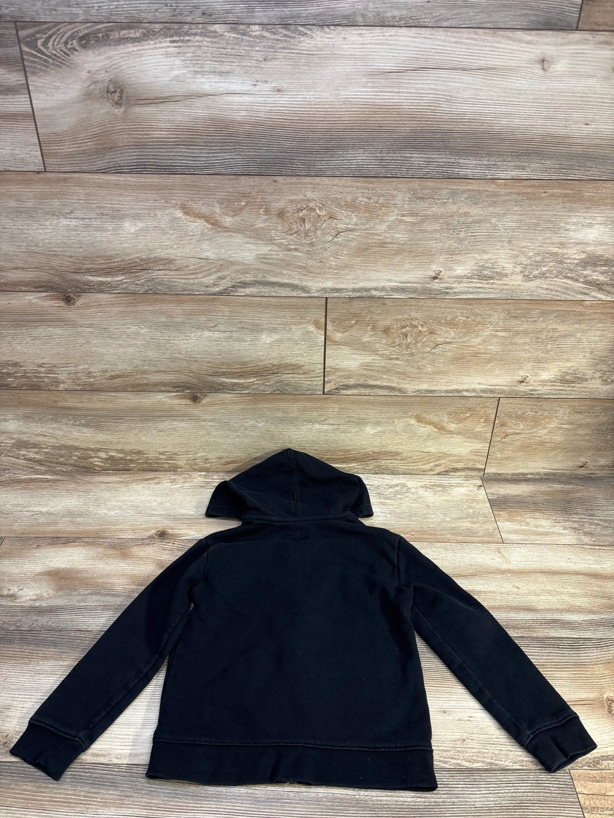 Back view of Cat & Jack black full-zip hooded jacket size 4/5T showing hood, long sleeves, and ribbed cuffs on wood background
