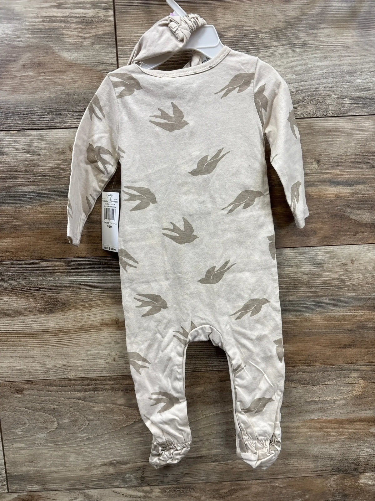 Neutral beige long sleeve baby romper with bird print and matching hat on wood background