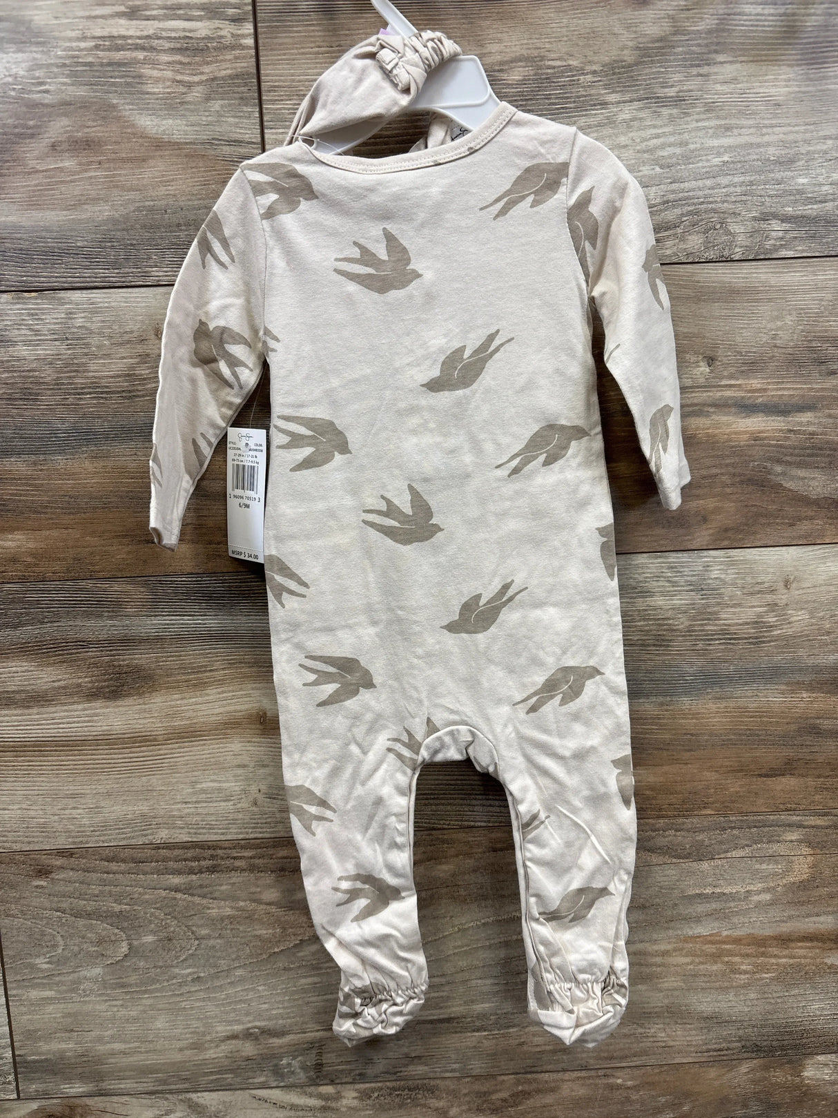 Neutral beige long sleeve baby romper with bird print and matching hat on wood background