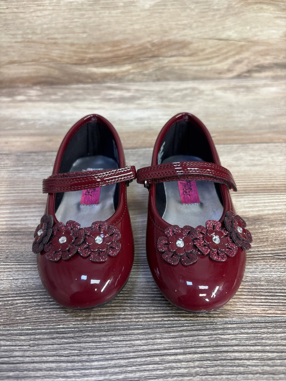 Front view of Rachel Shoes Lil’ Abelina flats in burgundy showcasing patent leather and glittery floral vamp accents