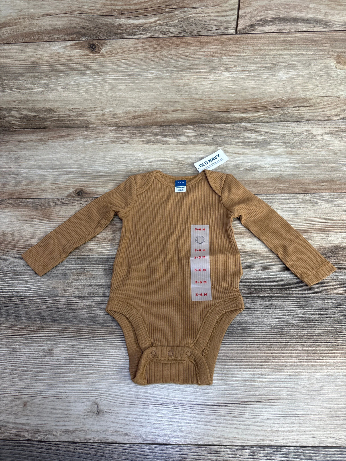 Brown ribbed long sleeve baby onesie 3-6 months size by Old Navy on wood floor