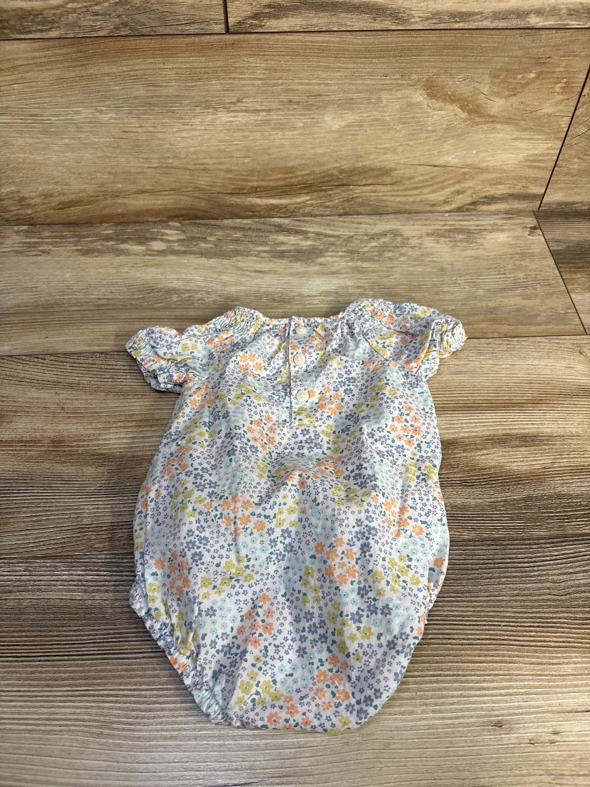 Front view of Just One You white floral bubble romper in size 3 months showcasing short sleeves and bubble hem on a wood floor