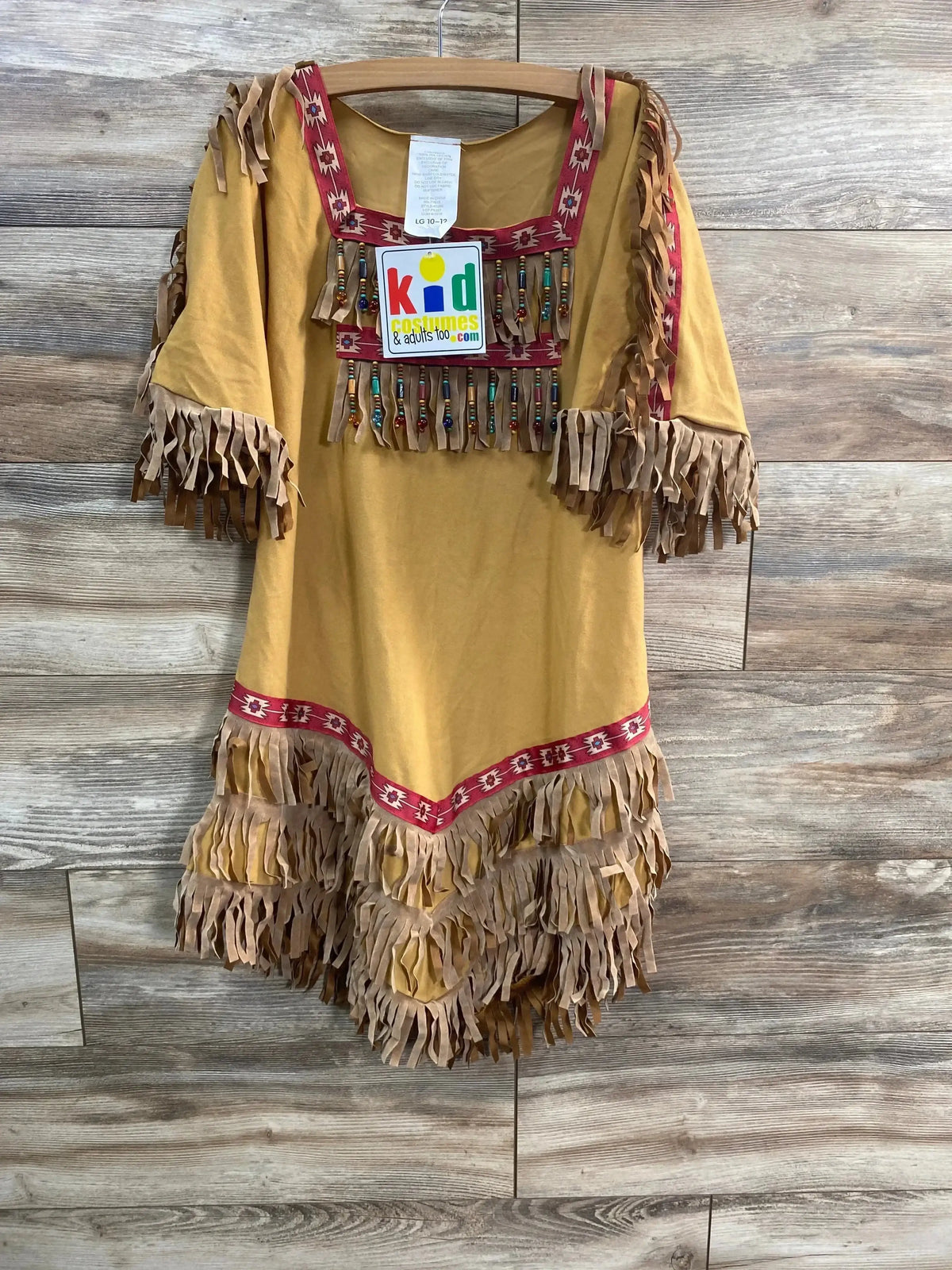 Front view of tan fringe children’s costume dress with beaded fringe, red trim, and layered hem on wood background