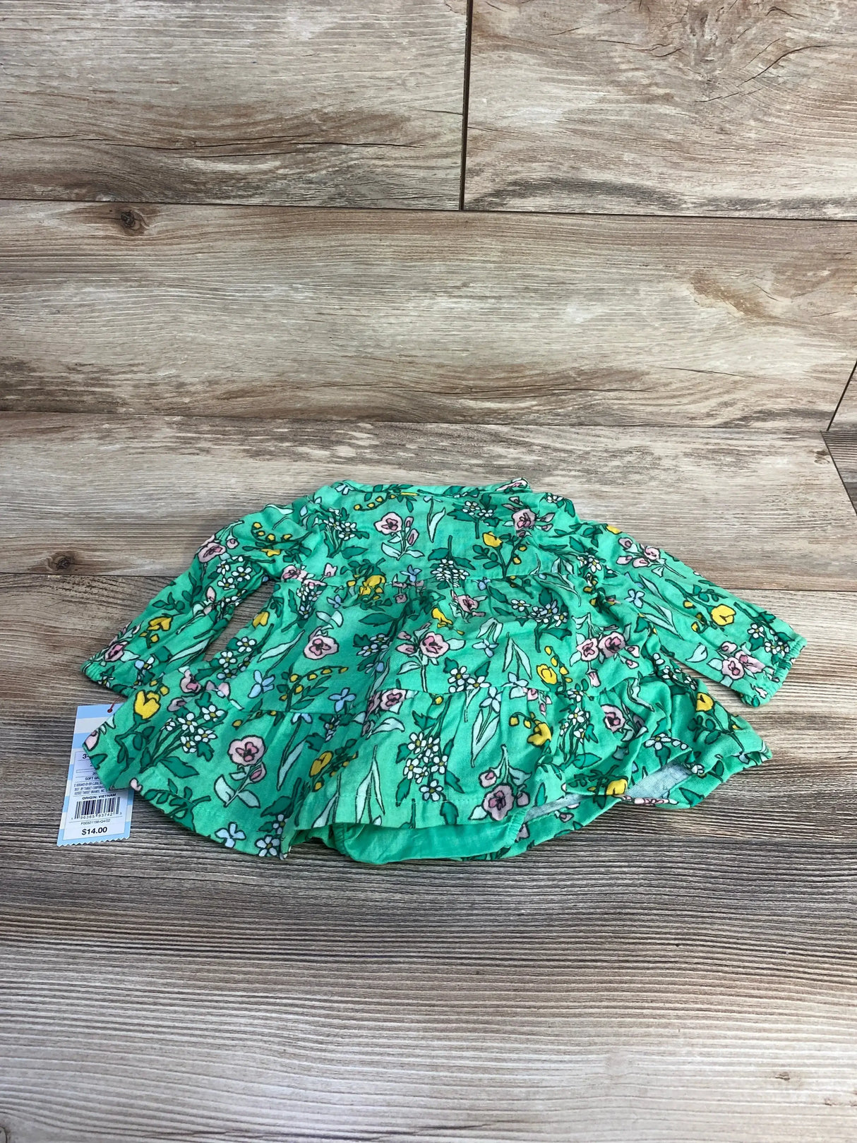 Flat lay of Cat & Jack green floral henley dress with matching bloomers, long sleeves and ruffled skirt on wood background