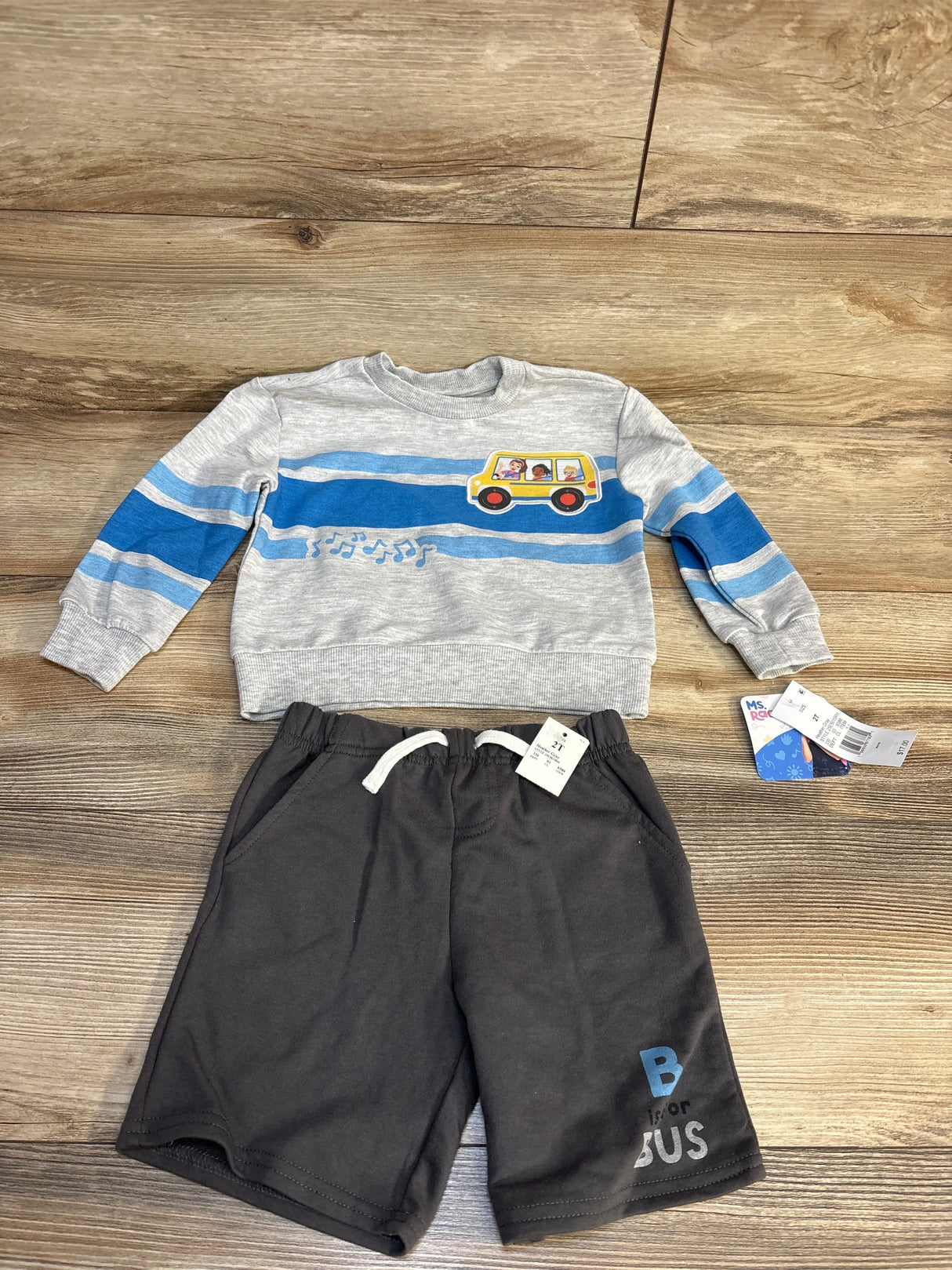 Toddler boy outfit with gray bus print sweater and black shorts on wood background