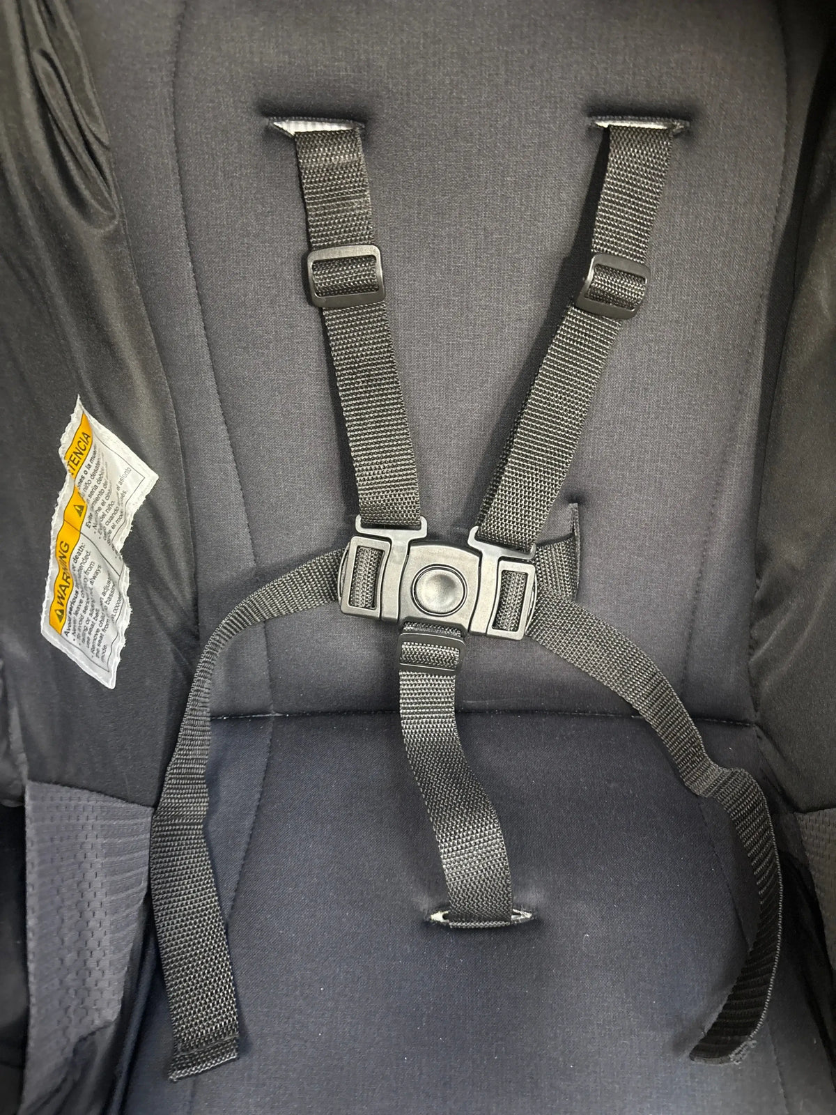 Close-up view of Graco Modes Pramette Stroller, Black showcasing five-point harness and central buckle with black padded seat background
