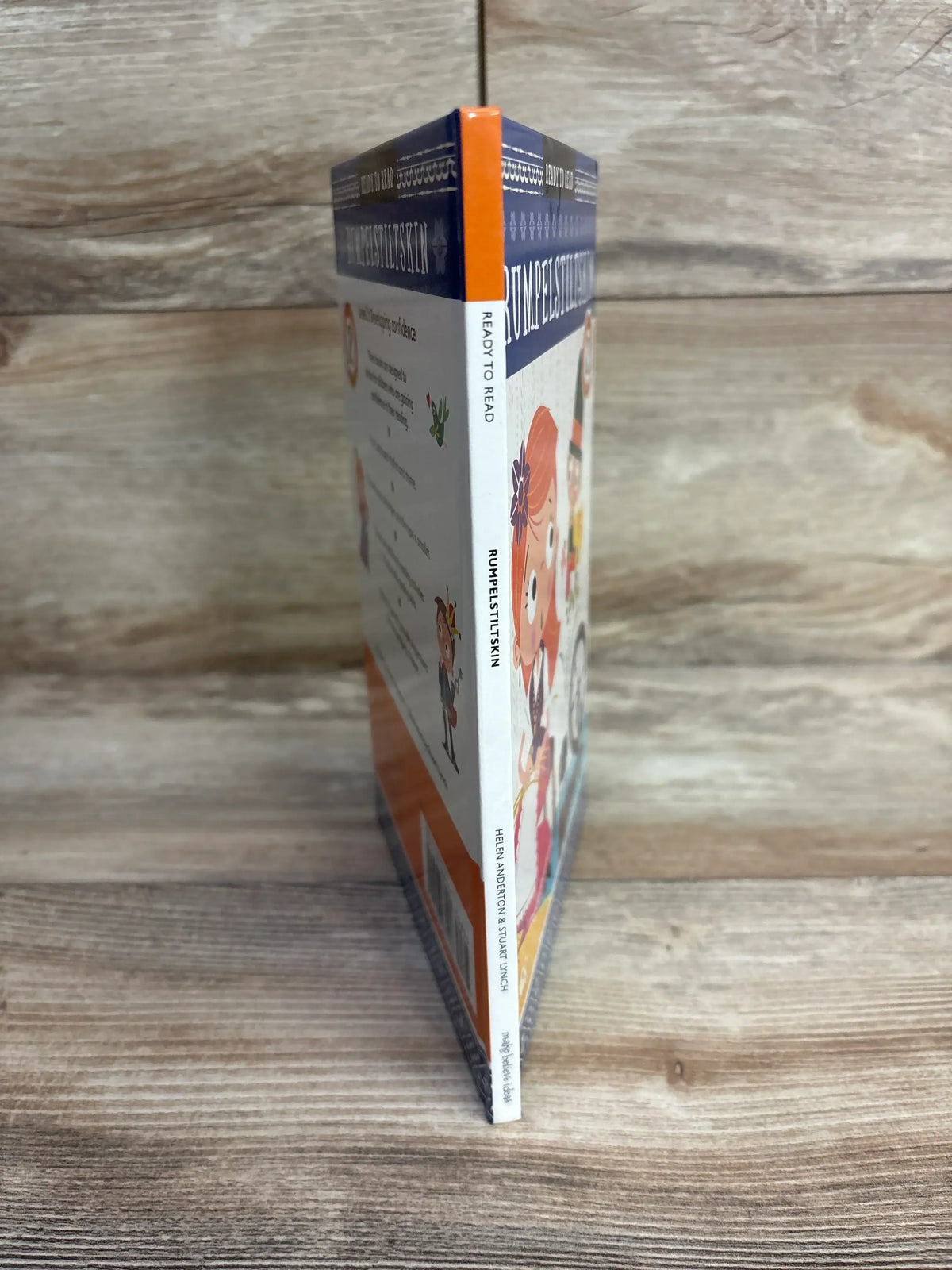 Children's illustrated Rumpelstiltskin book standing on wood background, ready to read edition