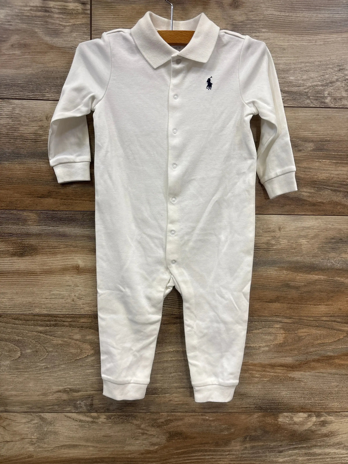 White baby romper with long sleeves, collar, snap buttons, and embroidered logo on chest