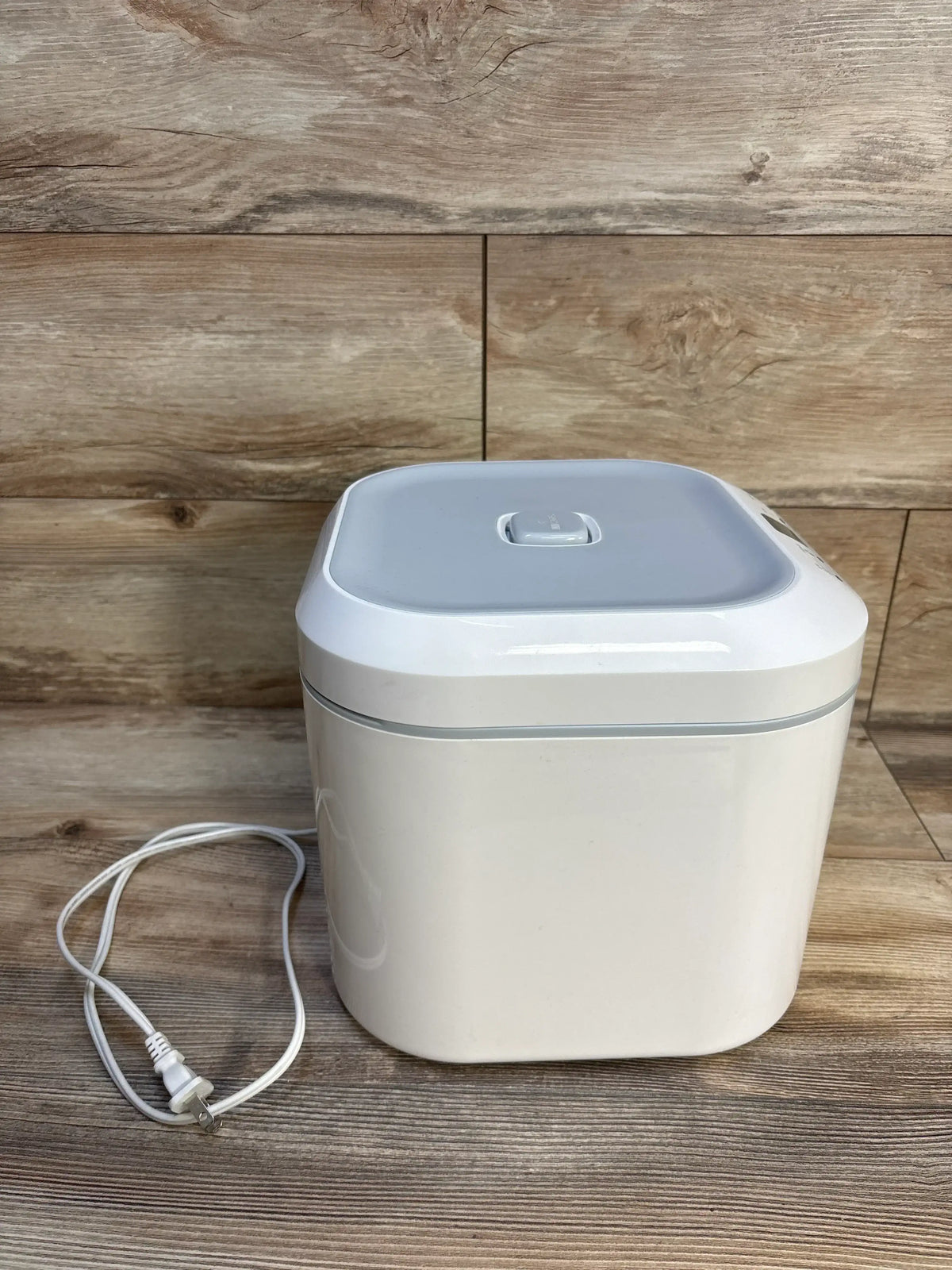 Angled front view of UV Care Multipurpose Sterilizer Lite 1 showing closed lid and power cord on wood background