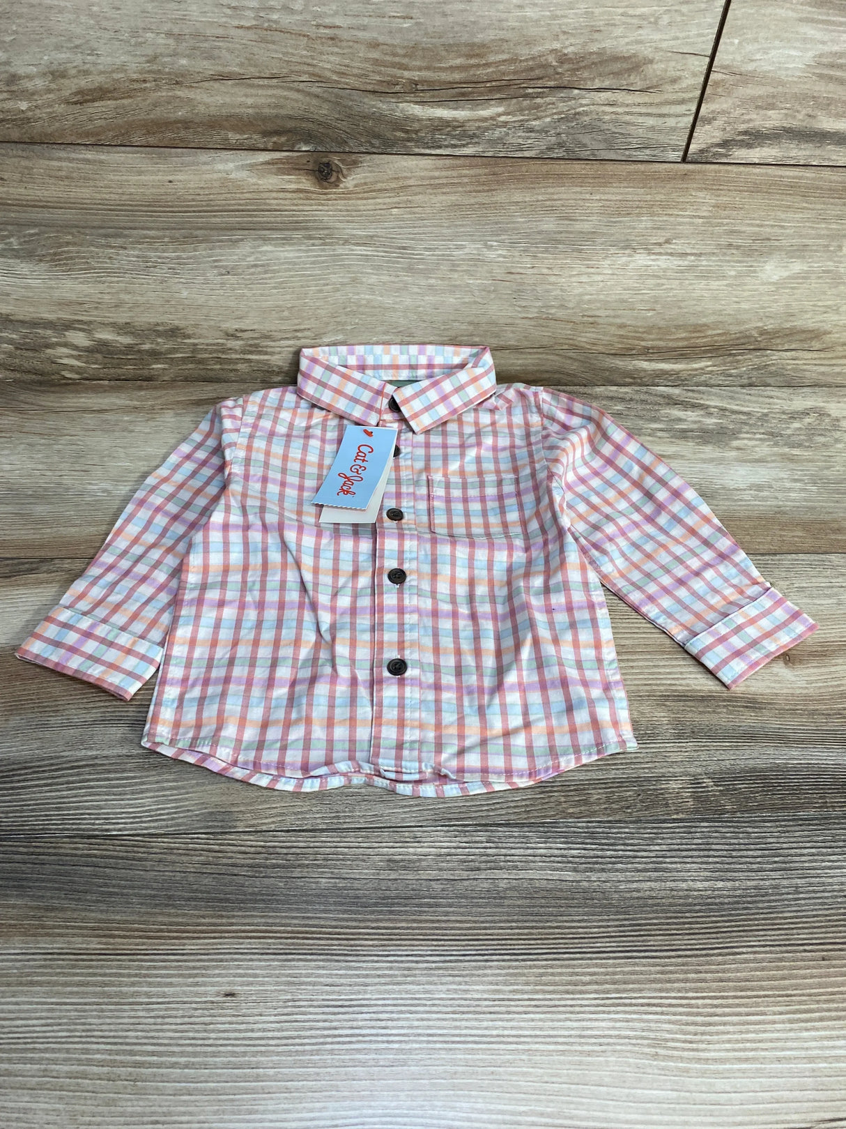 Flat lay of Cat and Jack toddler plaid button-up shirt, pink and orange checks, front buttons and spread collar, size 12 months on wood background