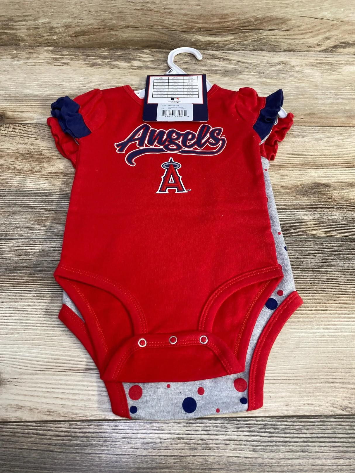 Top-down view of red Los Angeles Angels 2-piece baby onesie set (12M) with ruffle sleeves, Angels script and A logo on wood background