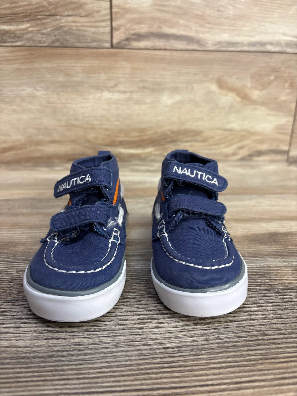 Navy blue Nautica toddler shoes with white soles on wood floor