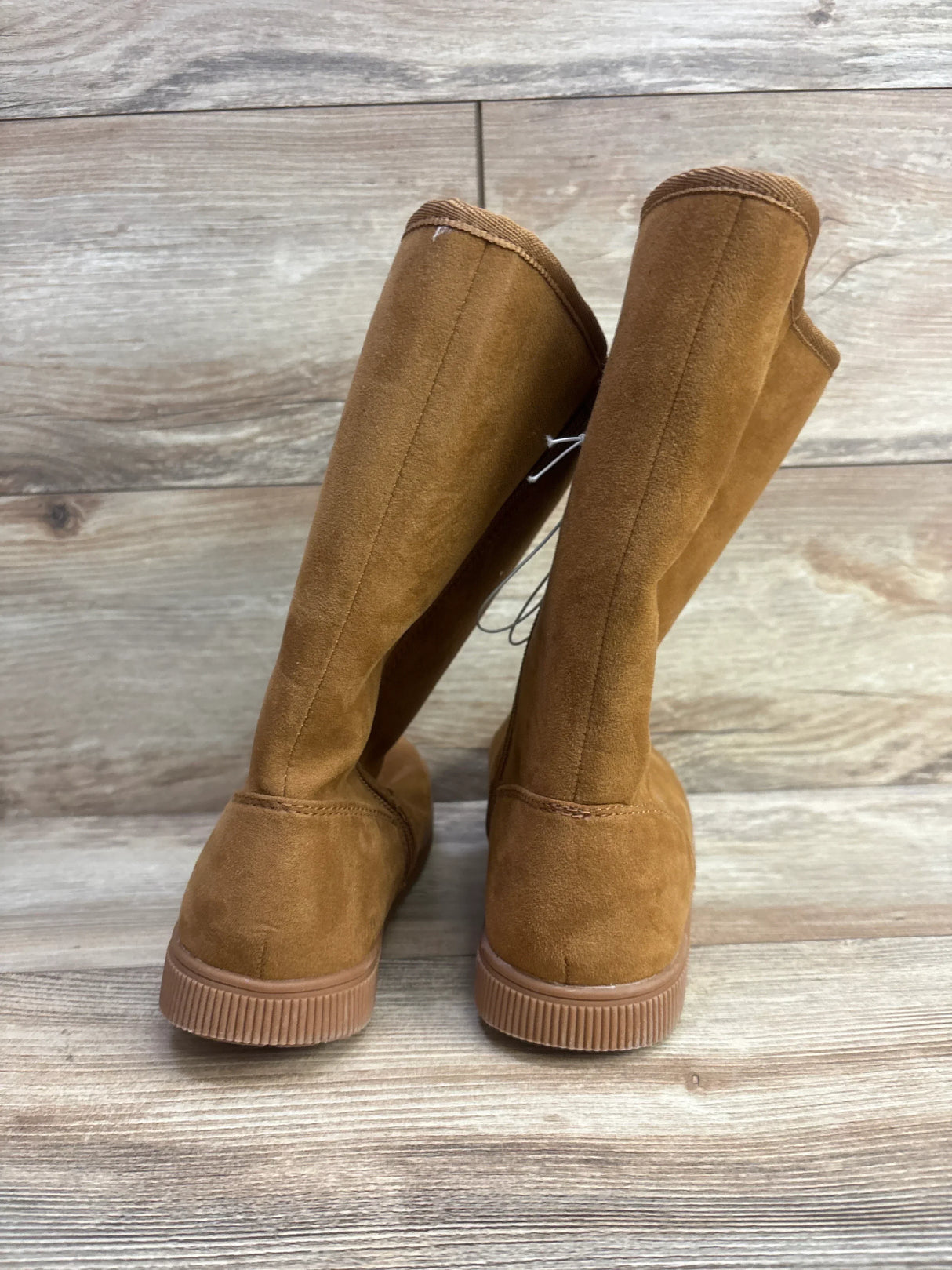 Back view of brown suede children's boots on wood floor