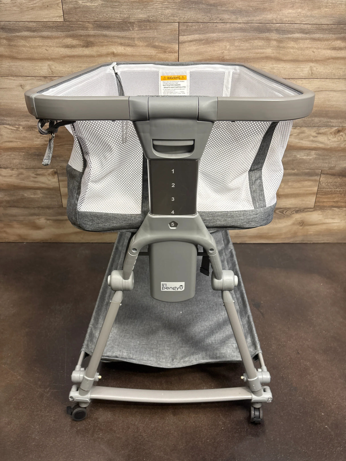 Baby bassinet with mesh sides, adjustable height, and gray frame on wheels