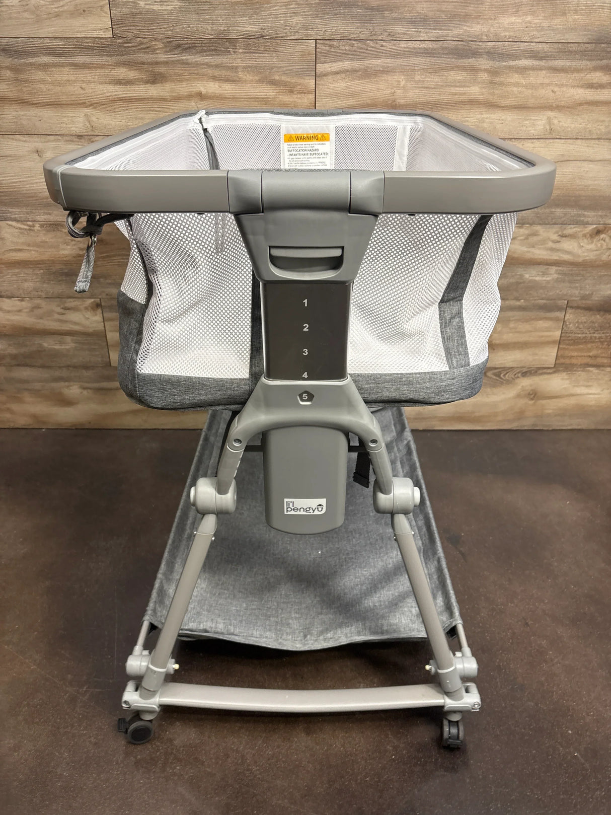 Baby bassinet with mesh sides, adjustable height, and gray frame on wheels