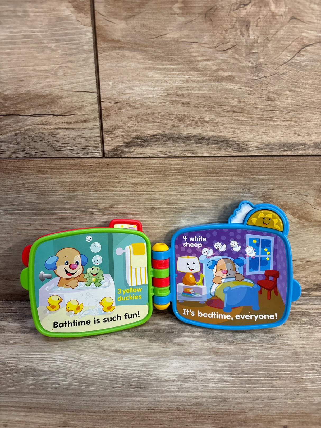 Open Fisher-Price Counting with Puppy electronic book showing bath and bedtime counting pages, colorful hinge on wood floor