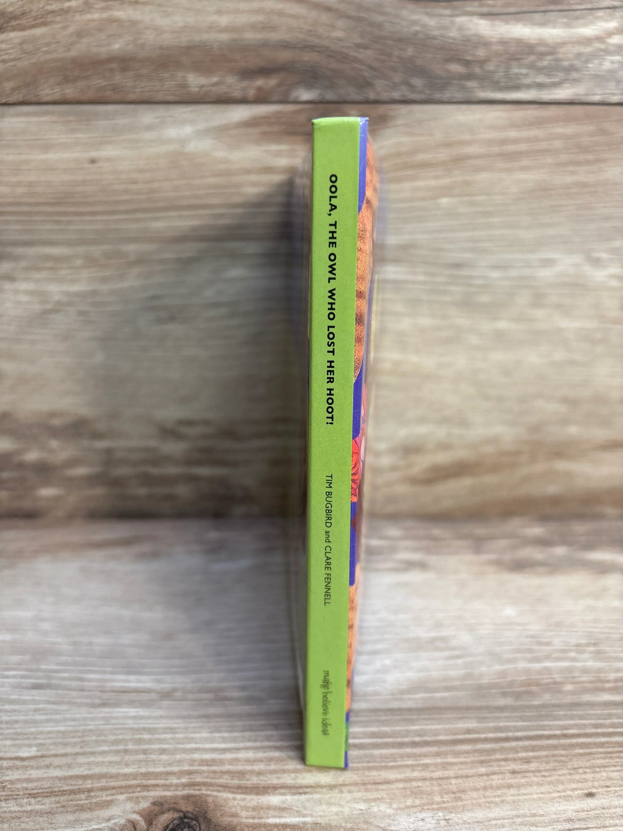 Spine of children's book 'Oola the Owl Who Lost Her Hoot' on wooden background
