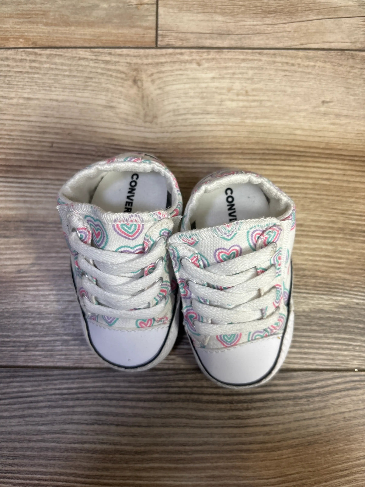 Top view of Converse All Star Cribster Easy-On Shoes, white with colorful heart pattern and white laces on wood flooring