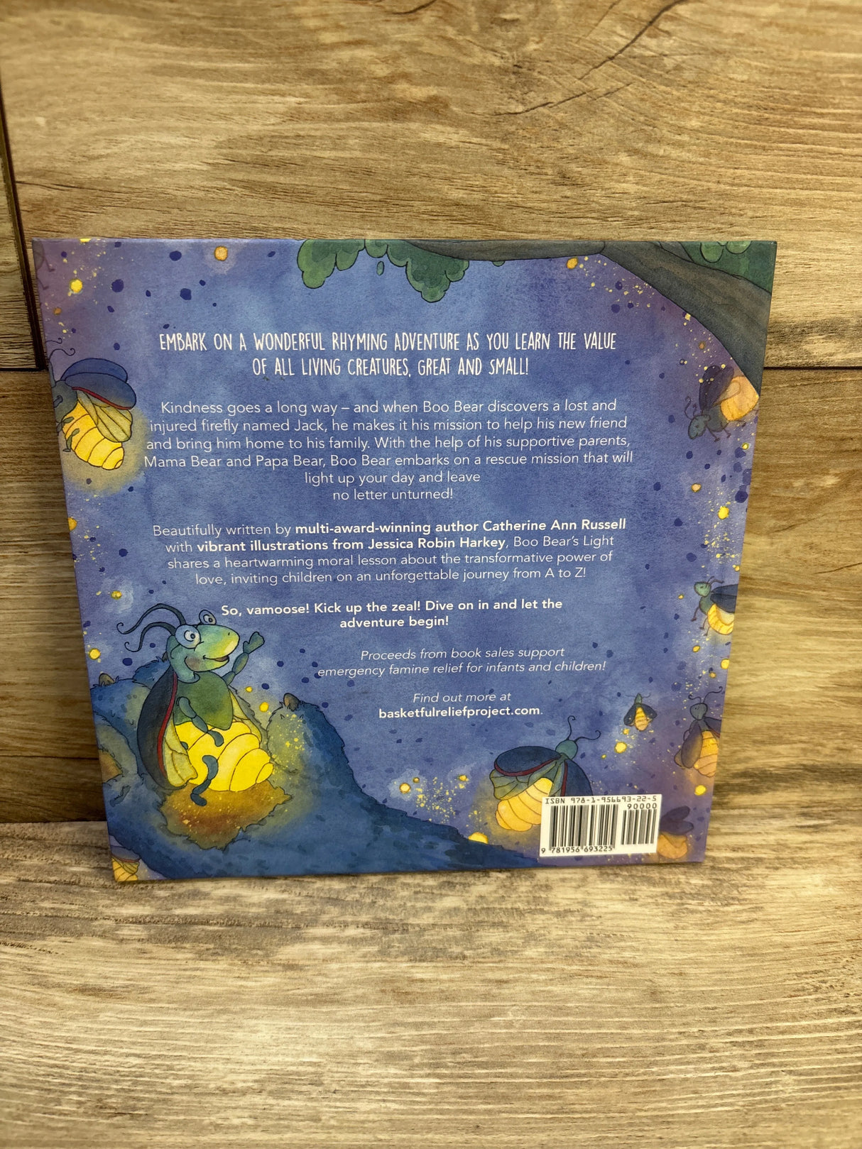 Back cover of Boo Bear’s Light hardcover showcasing illustrated glowing fireflies and synopsis text on a wooden background