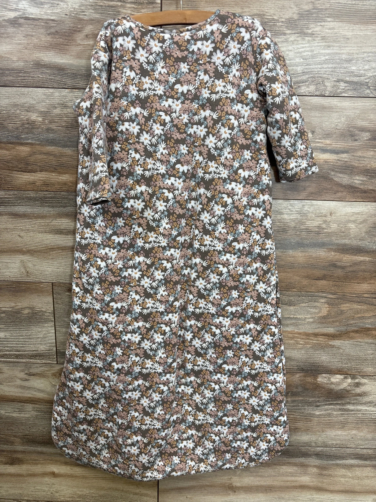Front view of günamüna 2.6 Tog long sleeve sleep sack in brown garden floral print showing full-length shape and long sleeves on wood background