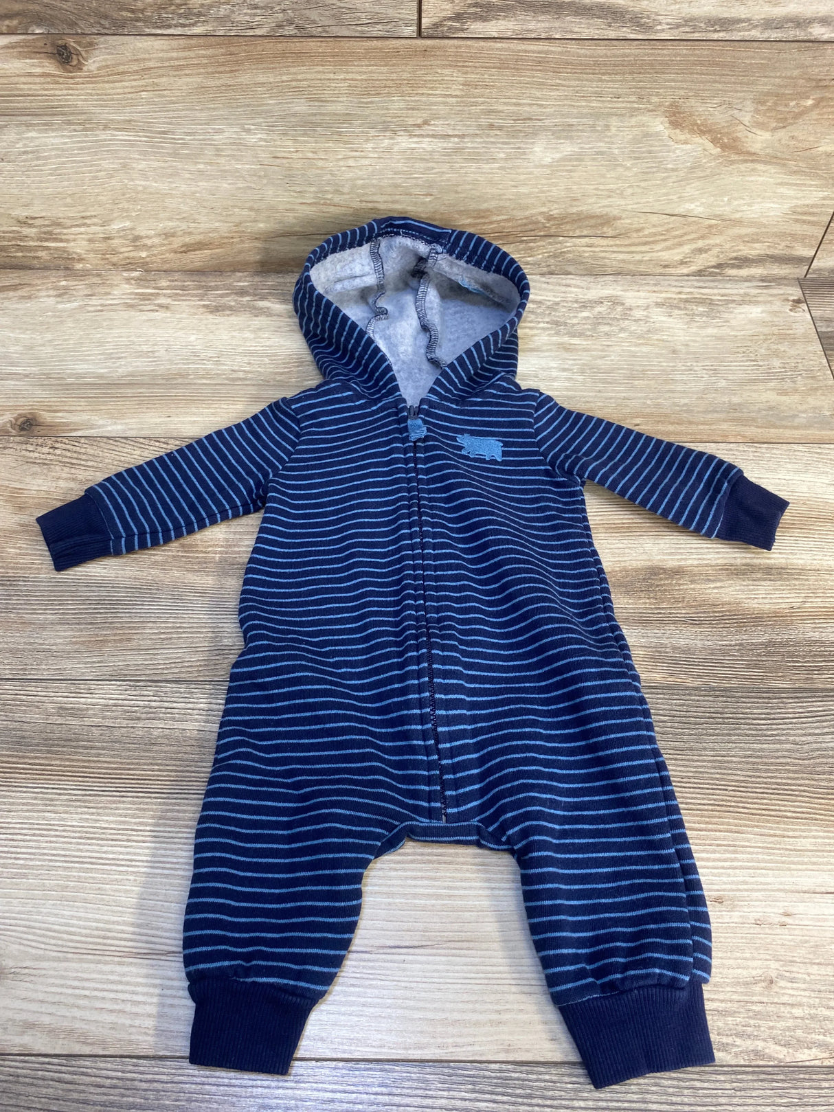 Navy blue striped hooded baby romper with zipper, laid flat on wooden floor.
