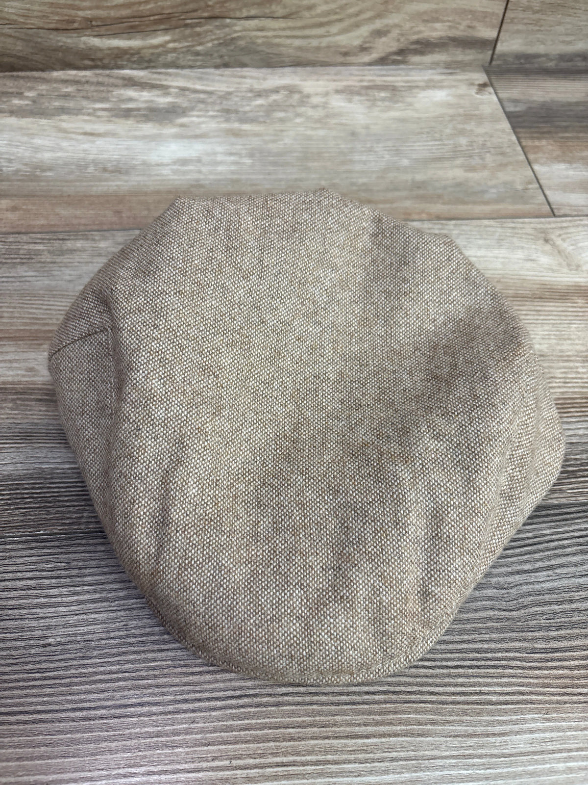 Jangoul kids newsboy tweed flat cap in tan, resting on a grey wooden surface.