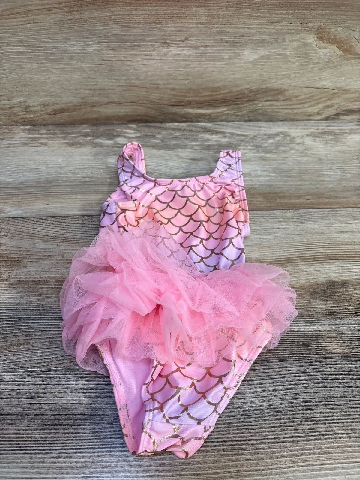 Flat lay of Wonder Nation toddler mermaid tutu swimsuit size 2T, pink with gold scale print and layered tulle on light wood