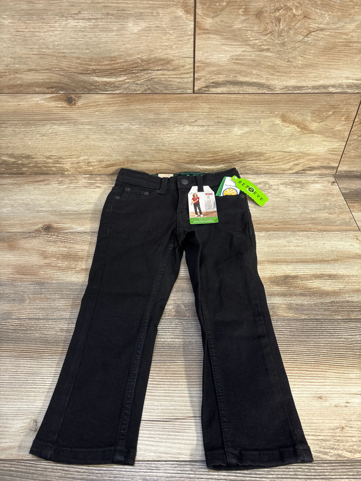New black Levi's 511 slim jeans for toddlers size 3T on a wooden background.
