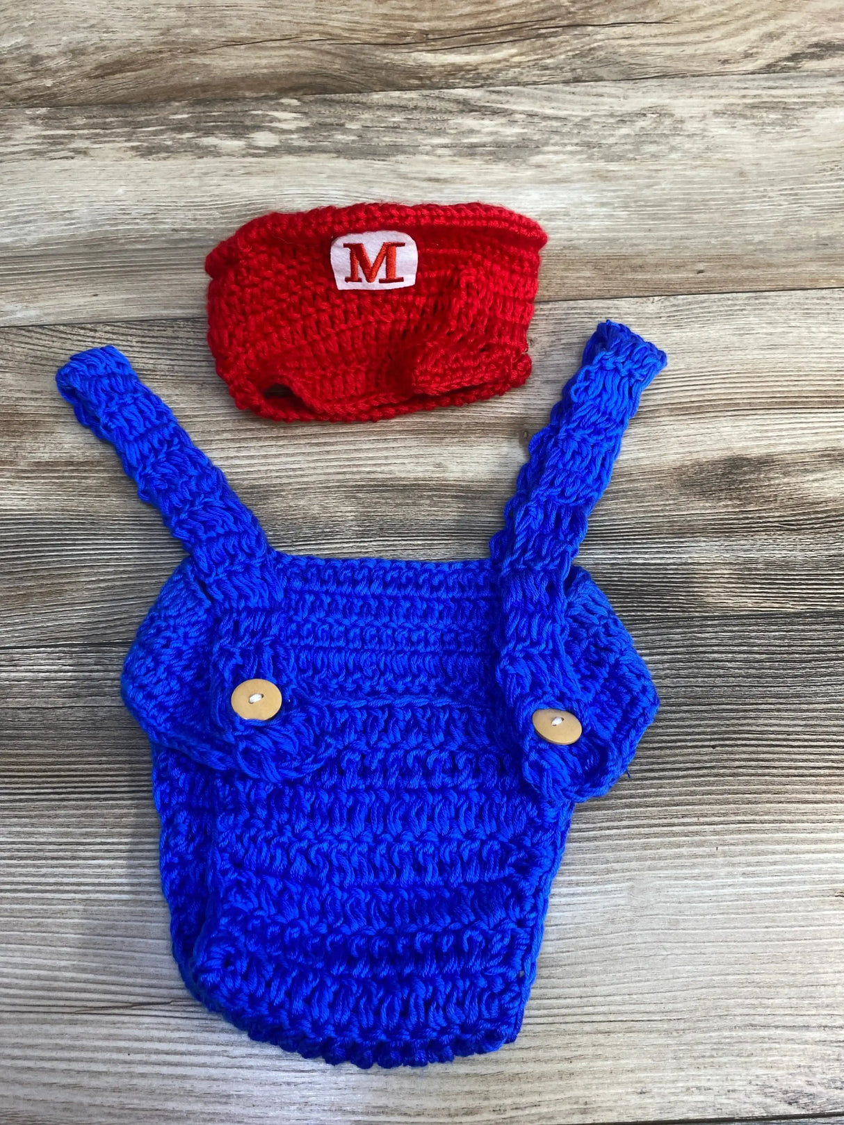Handcrafted blue crochet overalls with red hat, perfect for baby costumes or themed photoshoots.