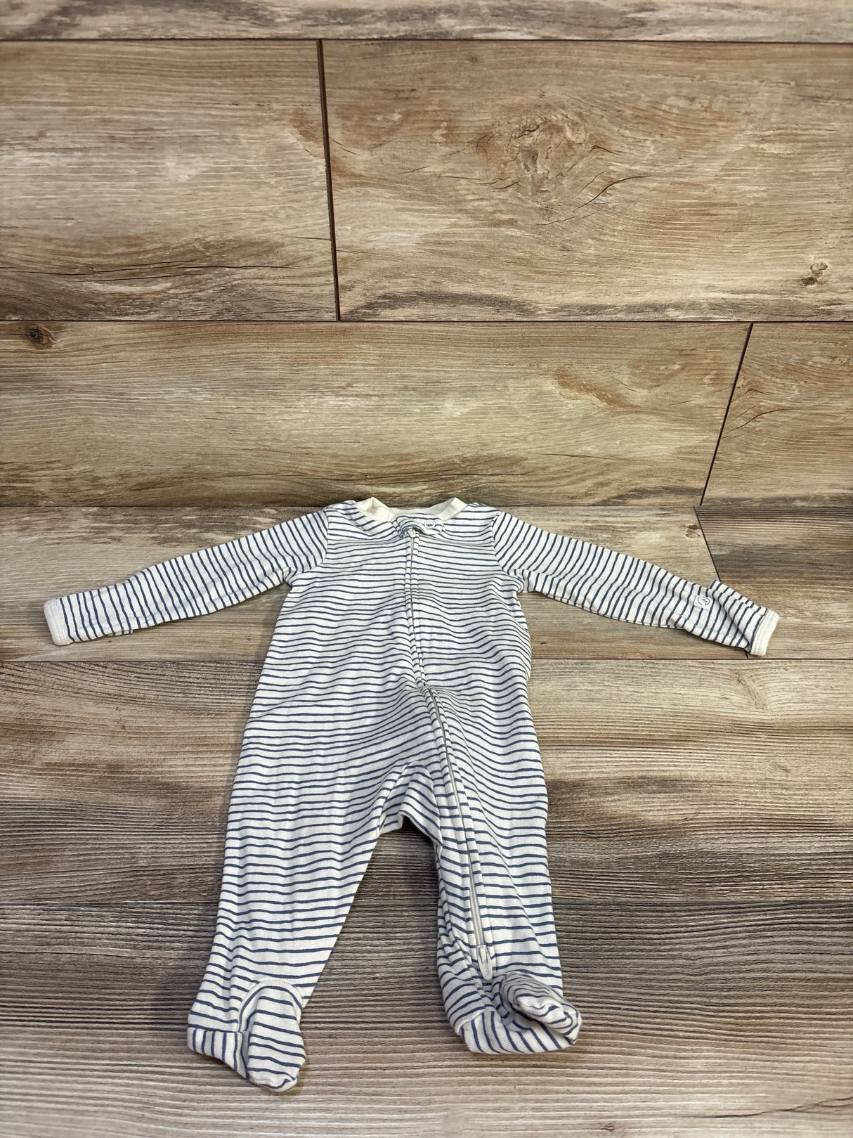 Front flat lay of Little Planet organic footed sleeper size 3M showing white fabric with thin navy stripes and front zipper on wood background