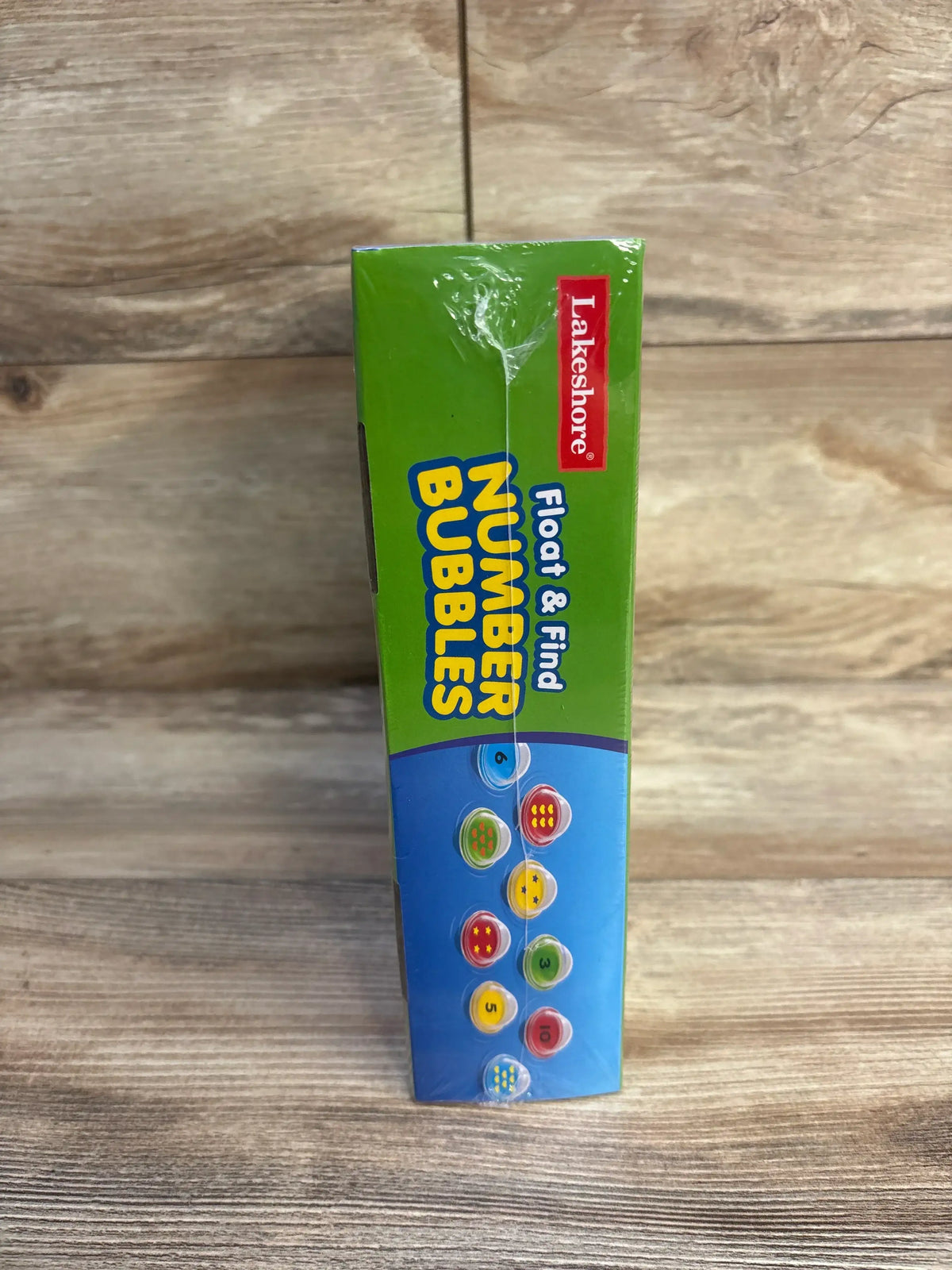 Front side view of Lakeshore Float & Find Number Bubbles box showing colorful numbered bubbles and branding on wood tabletop background