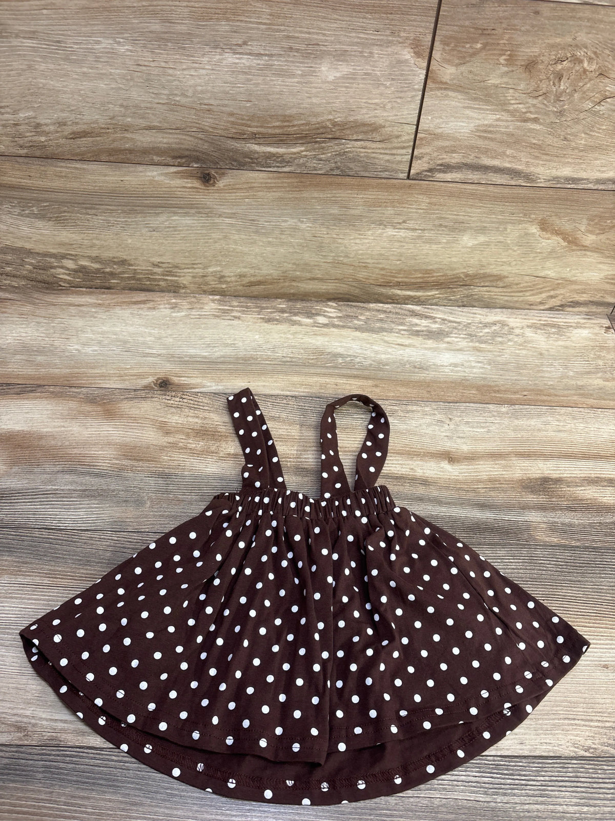 Top view of the brown Turkey suspender skirt showcasing white polka dots and gathered straps on a wood-look floor