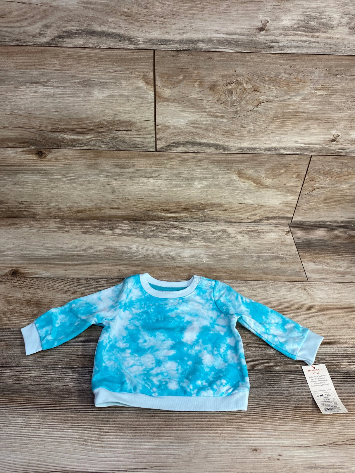 Blue and white tie-dye long sleeve baby sweatshirt with tag on wood background