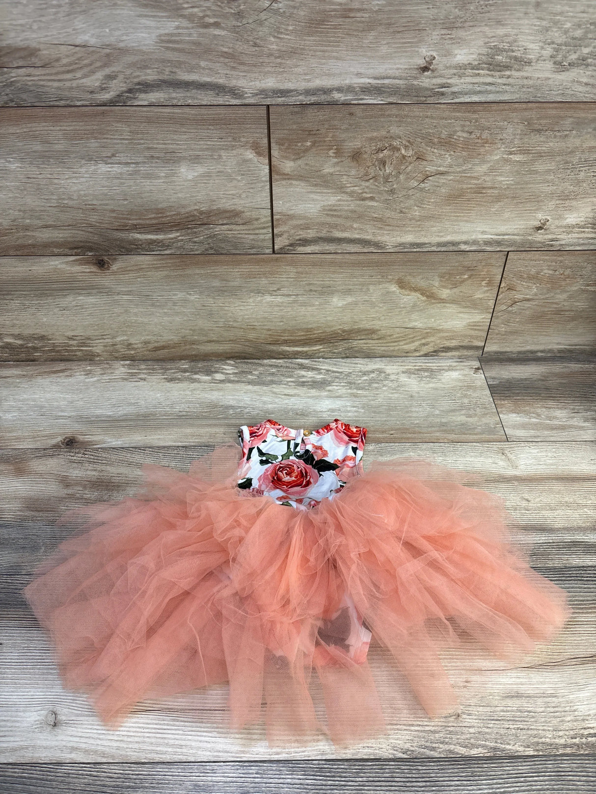 Flat lay of 12-18 month floral tulle tutu dress showing layered coral tulle skirt and rose print on wood background
