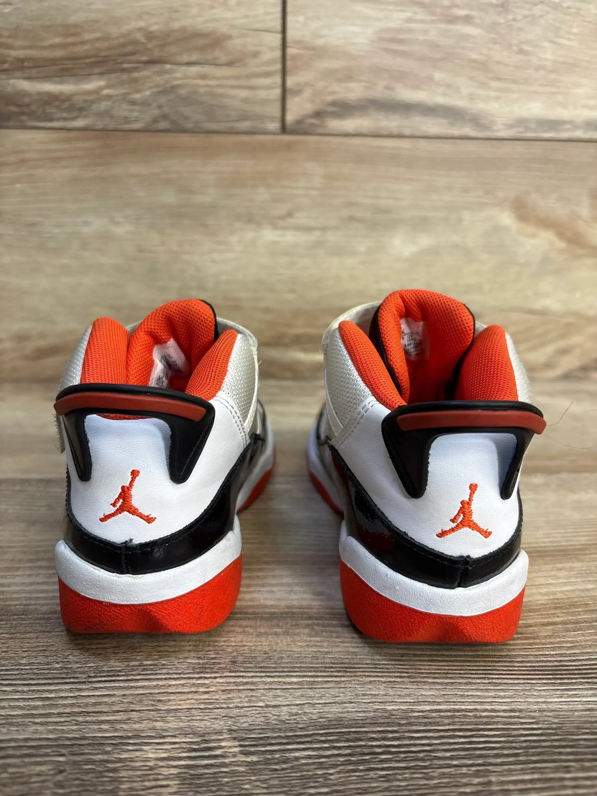 Rear of Air Jordan 6 Rings TD toddler sneakers in white, black, and team orange showing orange lining and Jumpman heel logo